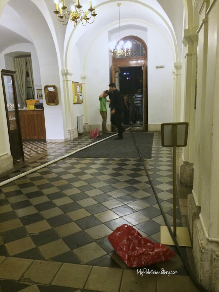 The shabab pulling water hoses through the lobby of the Austrian Hospice